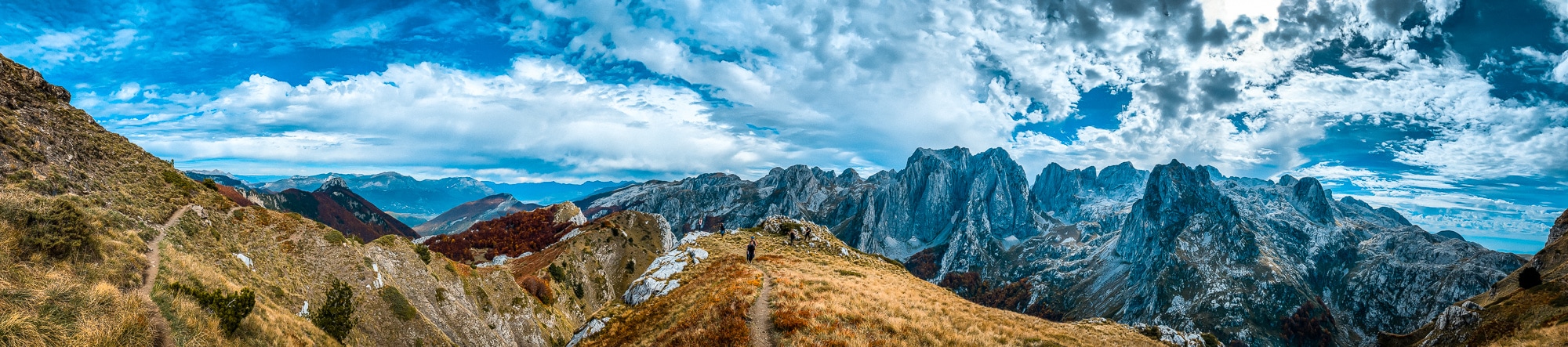 Fernes Panorama der albanischen Berge mit Wanderpfad, dramatischen Felsformationen und blauer Himmel, ideal für Natur- und Bergliebhaber in Albanien.