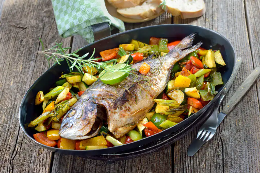 Oven fresh gilthead baked with rosemary on mixed summer vegetables, served with Italian ciabatta bread