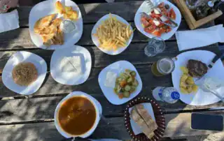 Pan de ajo, ensalada griega y patatas fritas en una mesa de madera, especialidades típicas albanesas, experiencia culinaria, cocina regional, aventura albanesa.