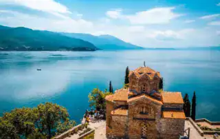 Adventure Albania, antiguo monasterio a orillas del lago Skutari con pintorescos paisajes de montaña y diseño de tejados turcos, combinación perfecta de naturaleza y cultura para vivir experiencias de viaje inolvidables.