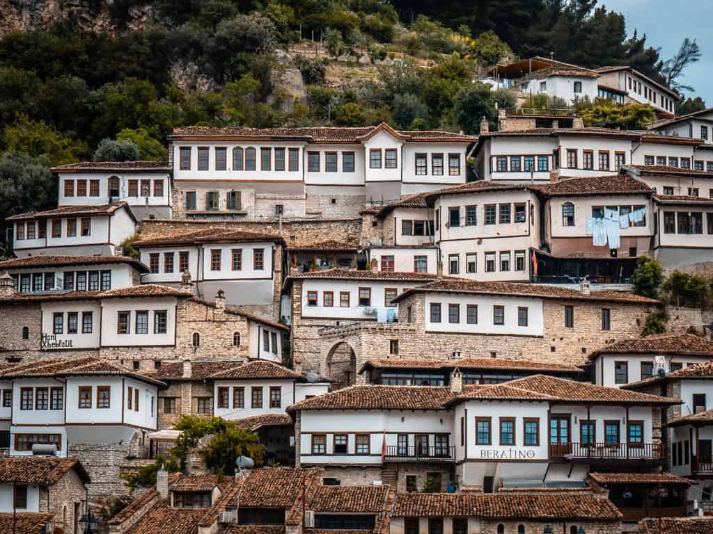 Bunte traditionelle albanische Häuser auf steiler Hügellandschaft in Berat, Albanien – UNESCO-Weltkulturerbe, bekannt für historische Architektur und beeindruckende Aussicht.