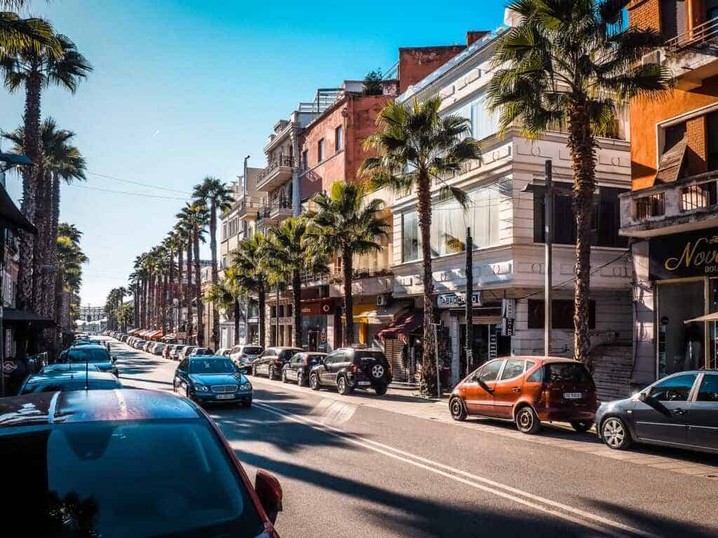 Avontuur Albanië, fascinerend stadsgezicht met palmbomen, moderne gebouwen, straatverkeer en levendige sfeer in Tirana, de bruisende hoofdstad van Albanië.