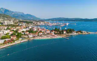 Costa de Albania con ciudad, puerto, montañas y aguas cristalinas, ideal para viajes de aventura y experiencias en Albania.
