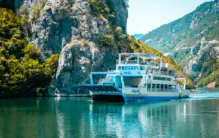 Barco transbordador en un río claro a través de un paisaje alpino en Albania.
