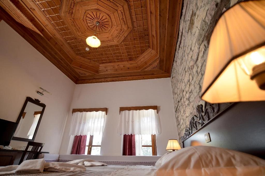 Holzgetäfelte Decke, romantisches Schlafzimmer, traditionelle albanische Unterkunft, gemütliche Inneneinrichtung mit rustikalem Charakter, perfekte Unterkunft in Albanien.