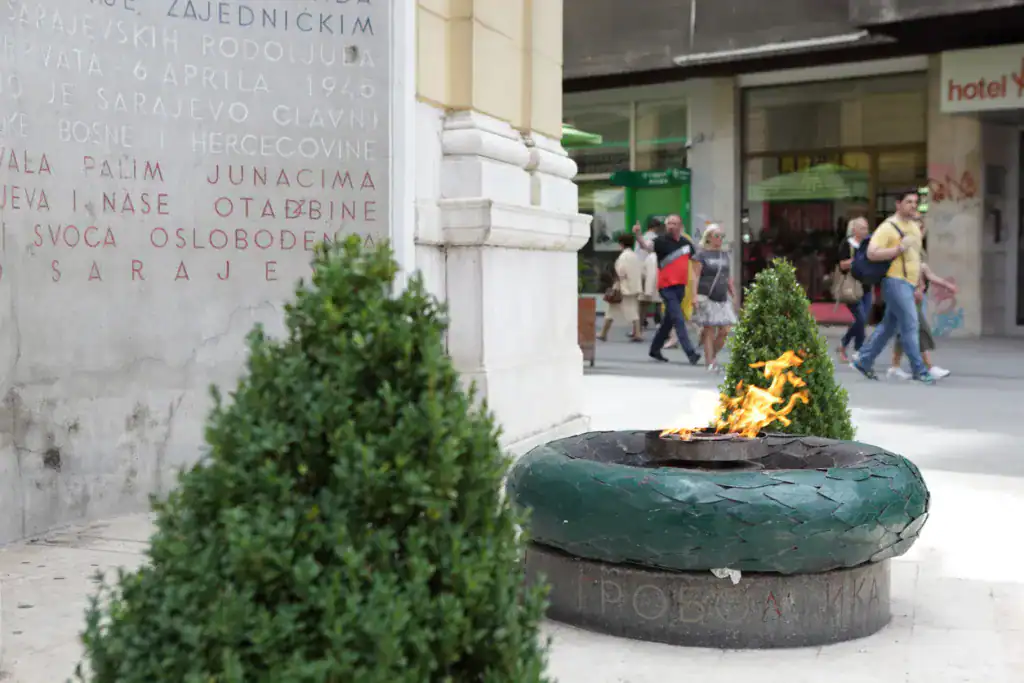Locals and Tourists continuously walk past the war memorial Vječna vatra located in the city of Sarajevo, Bosnia and Herzegovina.