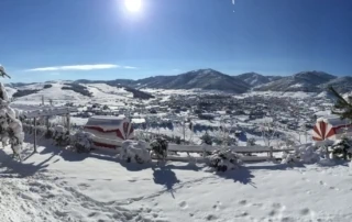 Weißer verschneiter Bergblick in Albanien, Winterlandschaft mit traditionellem Strandkorb und Zaun, klare blaue Himmel, ruhiges Winterparadies, Urlaub in Albanien im Schnee, Abenteuer Albanien.