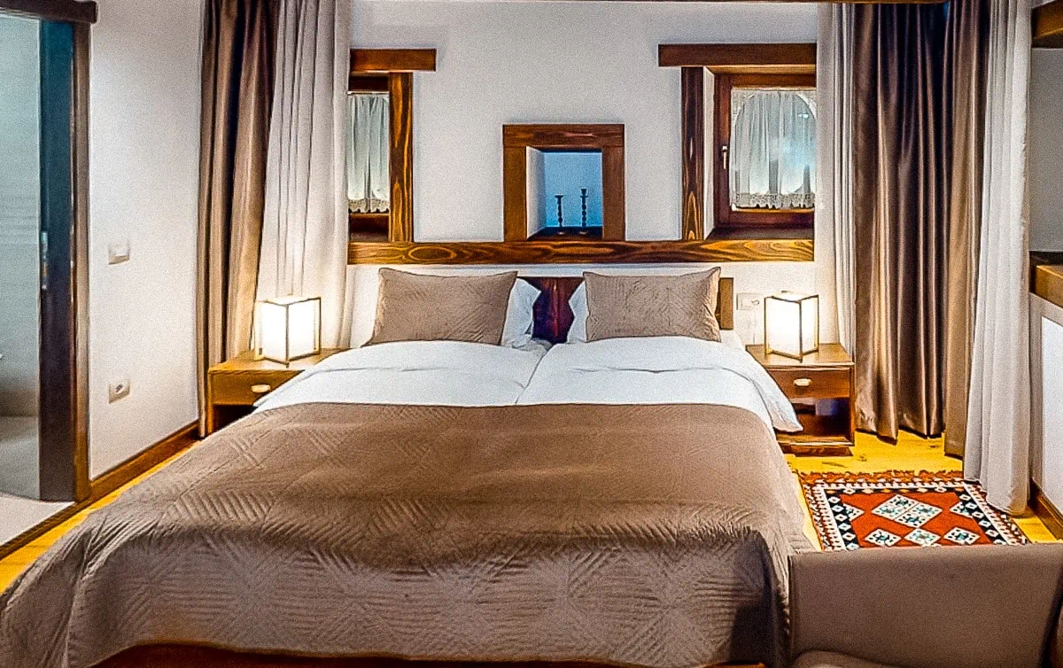 Gezellige hotelkamer in Peja met traditionele houten inrichting en comfortabele bedden, perfecte accommodatie voor je vakantie in Kosovo
