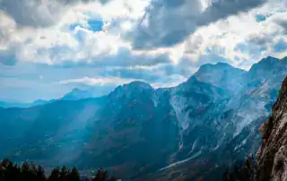 Majestuosas montañas albanesas con vastas formaciones nubosas, el telón de fondo perfecto para la aventura y la exploración de la naturaleza en Albania.