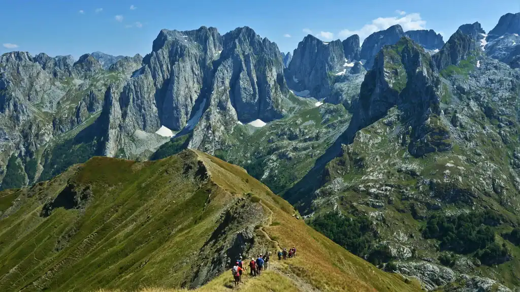Paisajes alpinos creativos en Albania con excursionistas recorriendo un sendero de montaña.