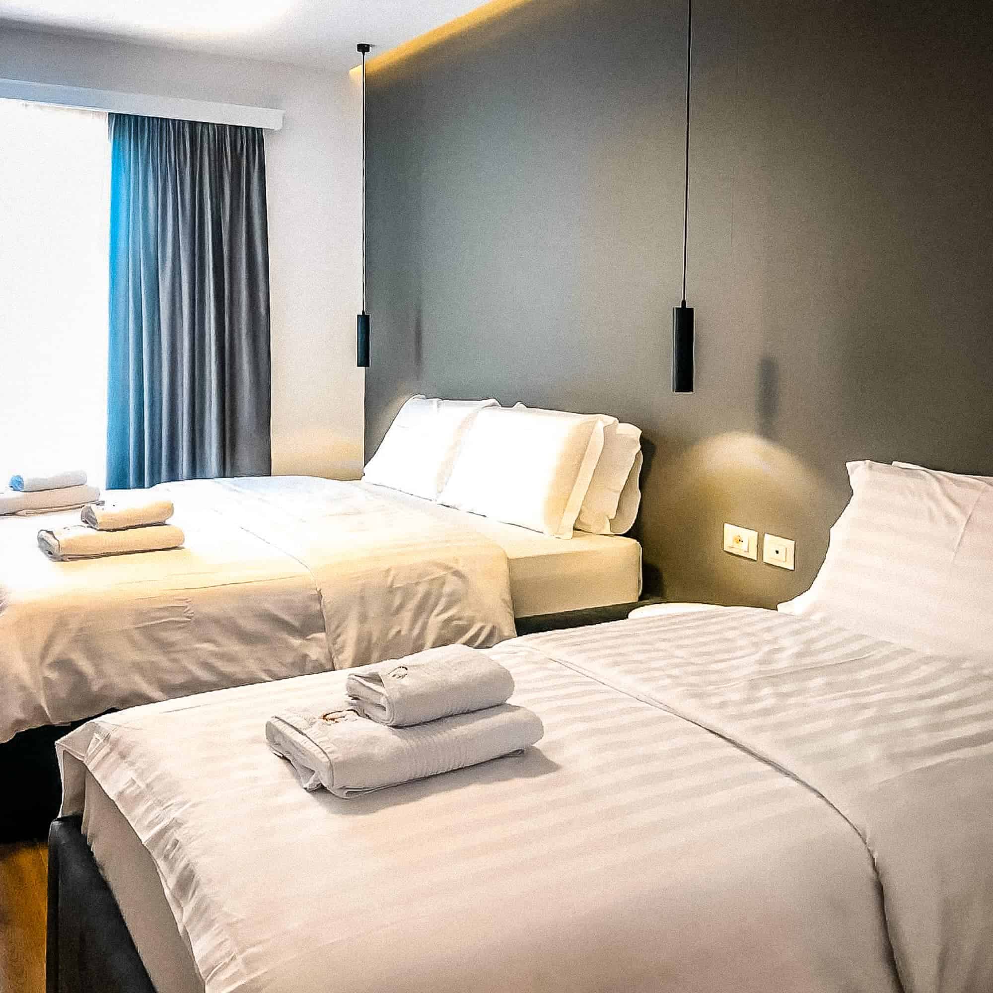 Bequeme Hotelzimmer mit modernen Betten, frischen weißen Bettwäsche und Handtüchern in einem eleganten, komfortablen Raum. Perfekt für einen erholsamen Aufenthalt in Albanien.