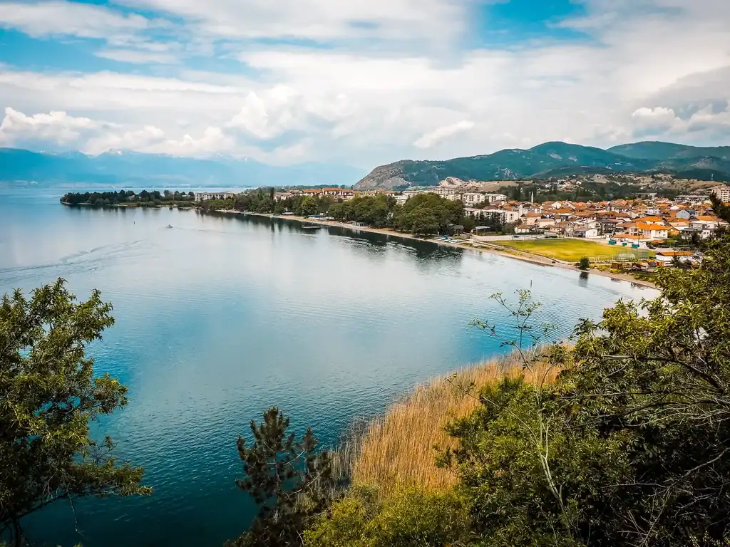 Schöne Albanische Stadt am See mit Bergen im Hintergrund, typisches mediterranes Stadtbild, ideal für Abenteuerurlaub in Albanien.