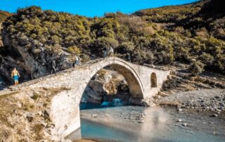 Antiguo puente de piedra en las montañas albanesas con río y naturaleza circundante, ideal para excursionistas y amantes de la naturaleza en Albania.