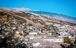Pueblo de montaña en Albania con casas blancas tradicionales y montañas circundantes al fondo.