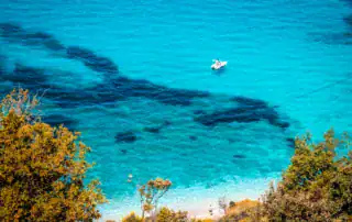 Aguas cristalinas en Albania en barco, contornos del fondo marino visibles, agua azul, playa idílica, paisaje costero espectacular, destino perfecto para unas vacaciones de aventura y naturaleza en Albania.