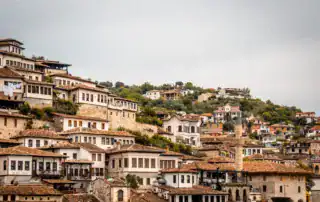 Antigua ciudad de Albania con casas tradicionales, muchos tejados de terracota y un pintoresco paisaje de colinas, ideal para viajes de aventura y turismo en Albania.