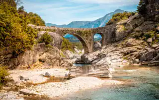 Antiguo puente de piedra en el paisaje albanés de montaña, río y naturaleza, ideal para aventuras y exploraciones en Albania.