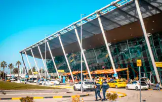 Moderno aeropuerto con fachada de cristal y acceso para sillas de ruedas en Albania, punto de llegada seguro para los viajeros.