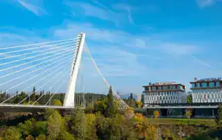 Moderno diseño de puente en Albania con edificios urbanos al fondo, el telón de fondo perfecto para una aventura albanesa.