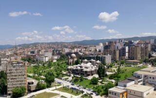 Vista de la ciudad de Tirana en Albania con un paisaje urbano moderno, espacios verdes y un centro cultural islámico histórico, rodeado de montañas, ideal para la aventura y la exploración en Albania.