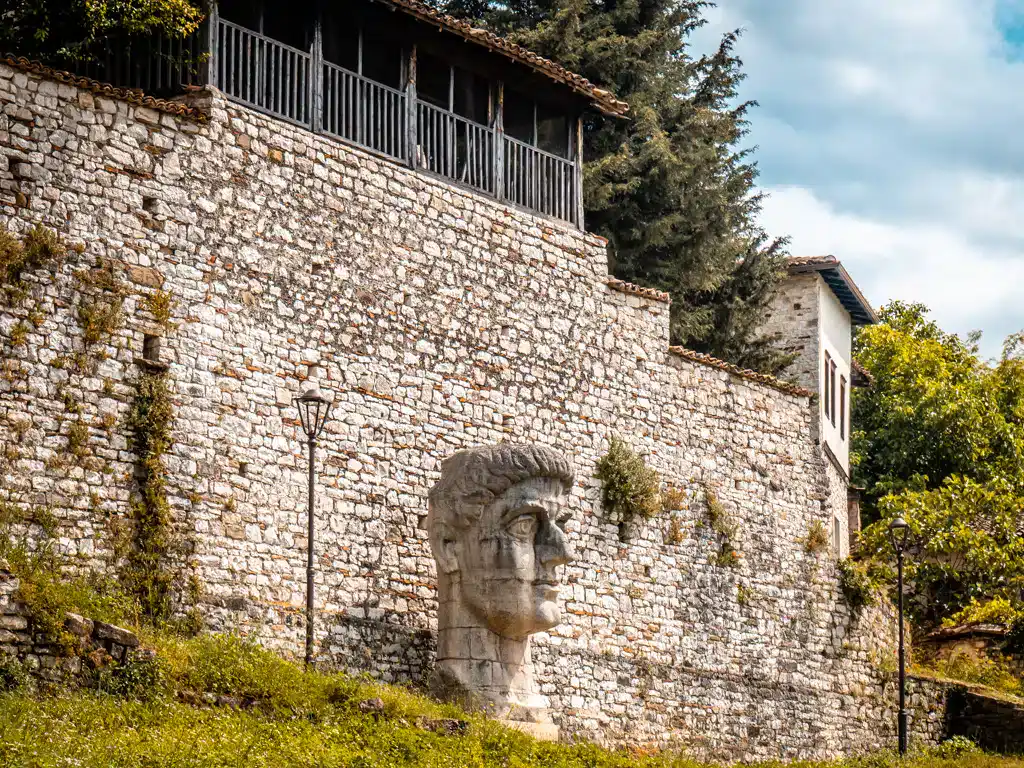 Antigua muralla de Albania con escultura romana, Vista histórica en Albania, Aventura Albania, Experiencias naturales y culturales, Historia y arquitectura.