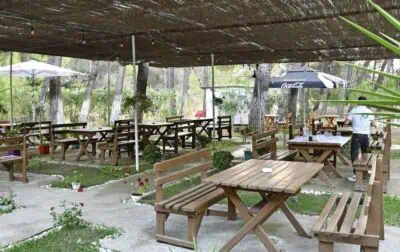 Gemütliche Außenwirtschaft in Albanien mit Holz-Mahagonie-Tischen und Bambus-Pavillon, ideal für entspanntes Essen im Grünen.