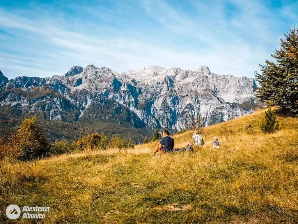 Atemberaubende Berglandschaft in Albanien mit Wanderern auf einer grünen Wiese und imposanten Gipfeln im Hintergrund. Perfekt für Naturliebhaber und Abenteuerurlaub in Albanien.