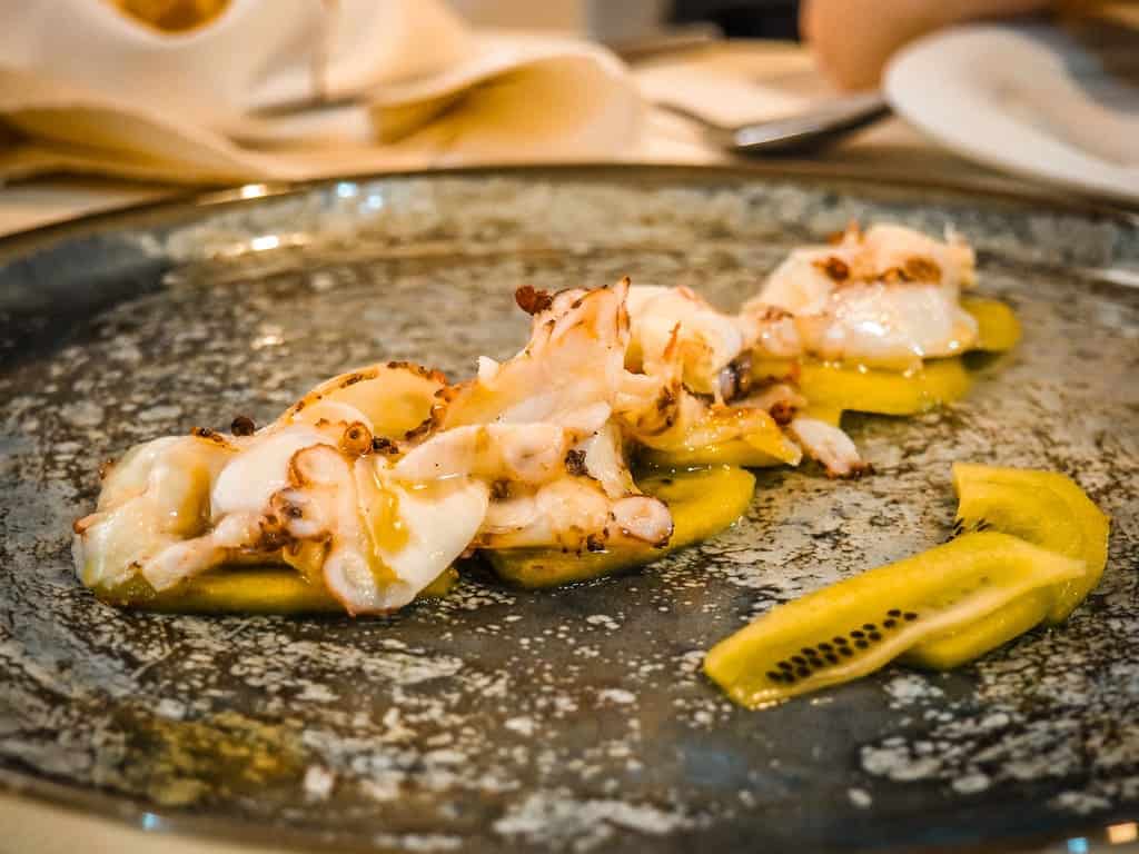 Marisco frito con kiwi y limones, típico de la cocina albanesa, servido en un plato rústico.