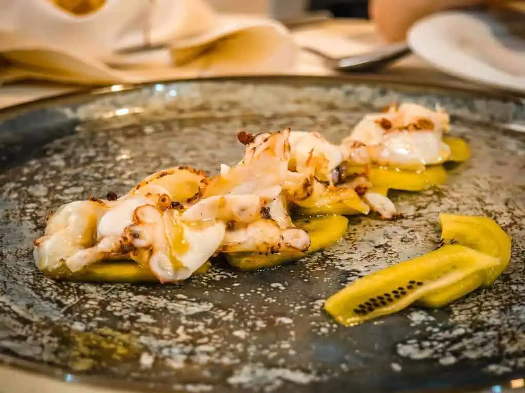 Gebratene Meeresfrüchte mit Kiwi und Zitronen, typisch albanische Küche, serviert auf rustikalem Teller.