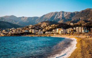 Vista descendente de la Riviera albanesa con montañas, ciudad y playa, lugar perfecto para la aventura y la relajación en Albania.