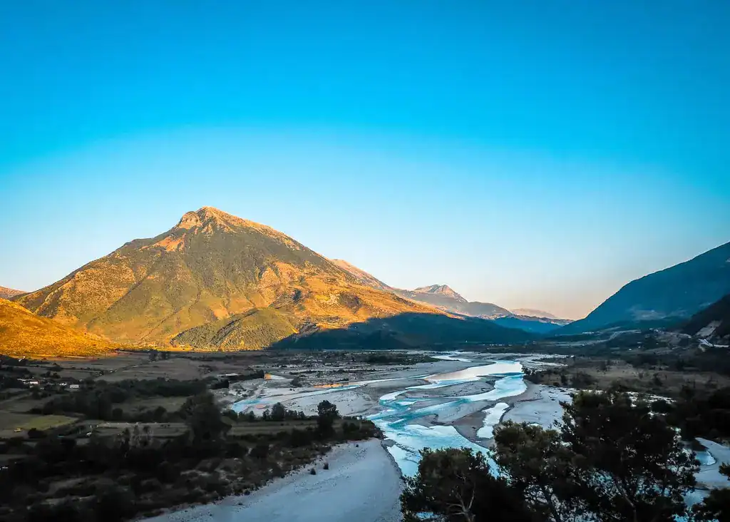 Avontuur Albanië: Indrukwekkende uitzichten op de bergen en de rivier de Vjosa in het avondlicht, de perfecte achtergrond voor natuur- en outdoorliefhebbers. Ontdek de ongerepte schoonheid van Albanië voor een onvergetelijke vakantie.